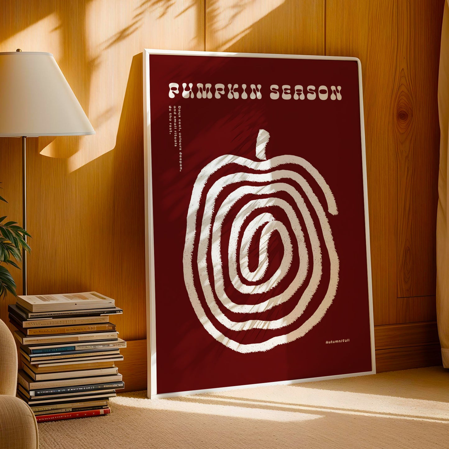 a poster with a large spiral design on a red background, placed on a wooden surface next to a stack of books and a lamp.