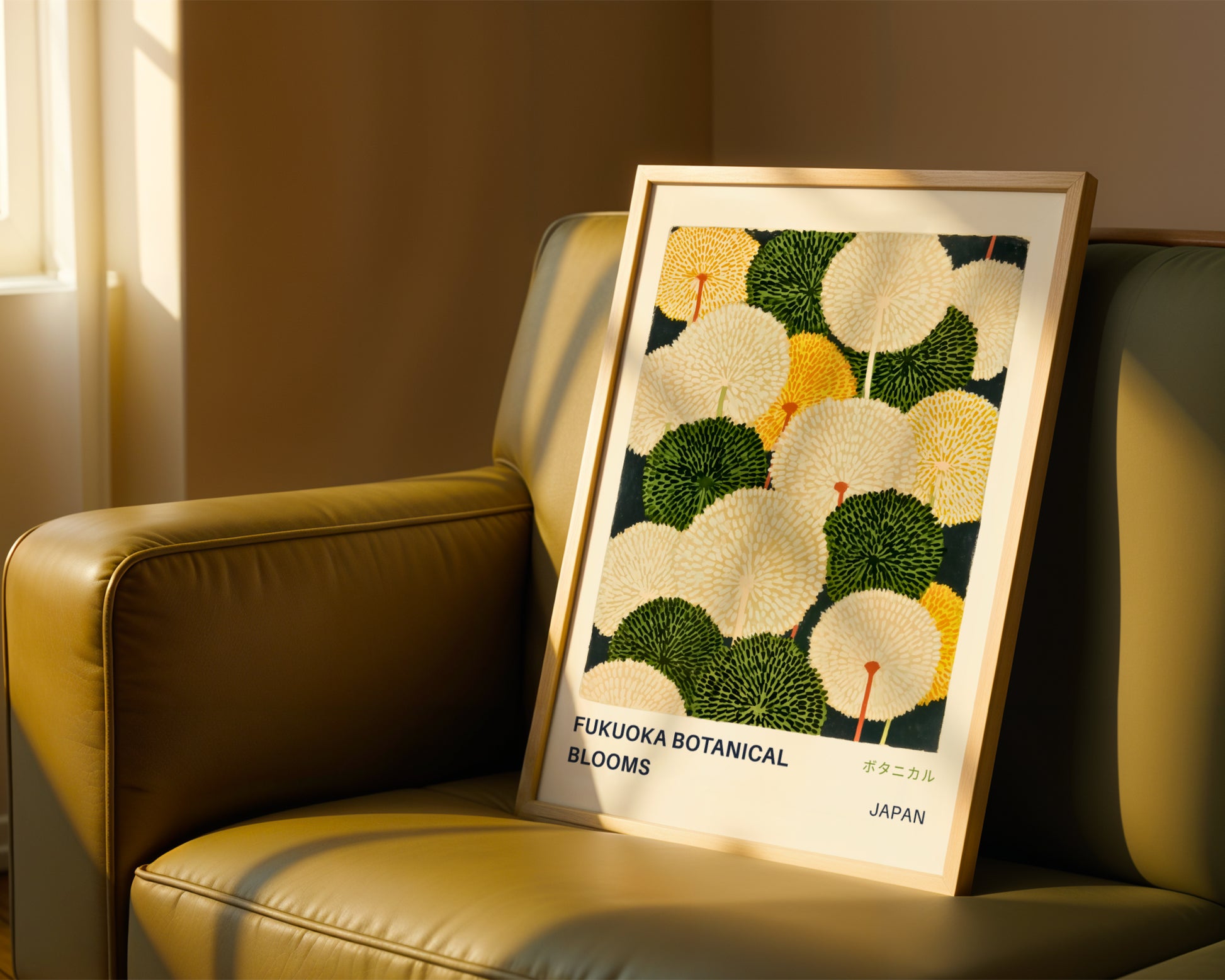 a framed poster of a floral design with the text "FUJOKA BOTANICAL BLOOMS" and "JAPAN" printed on it, placed on a brown leather couch.