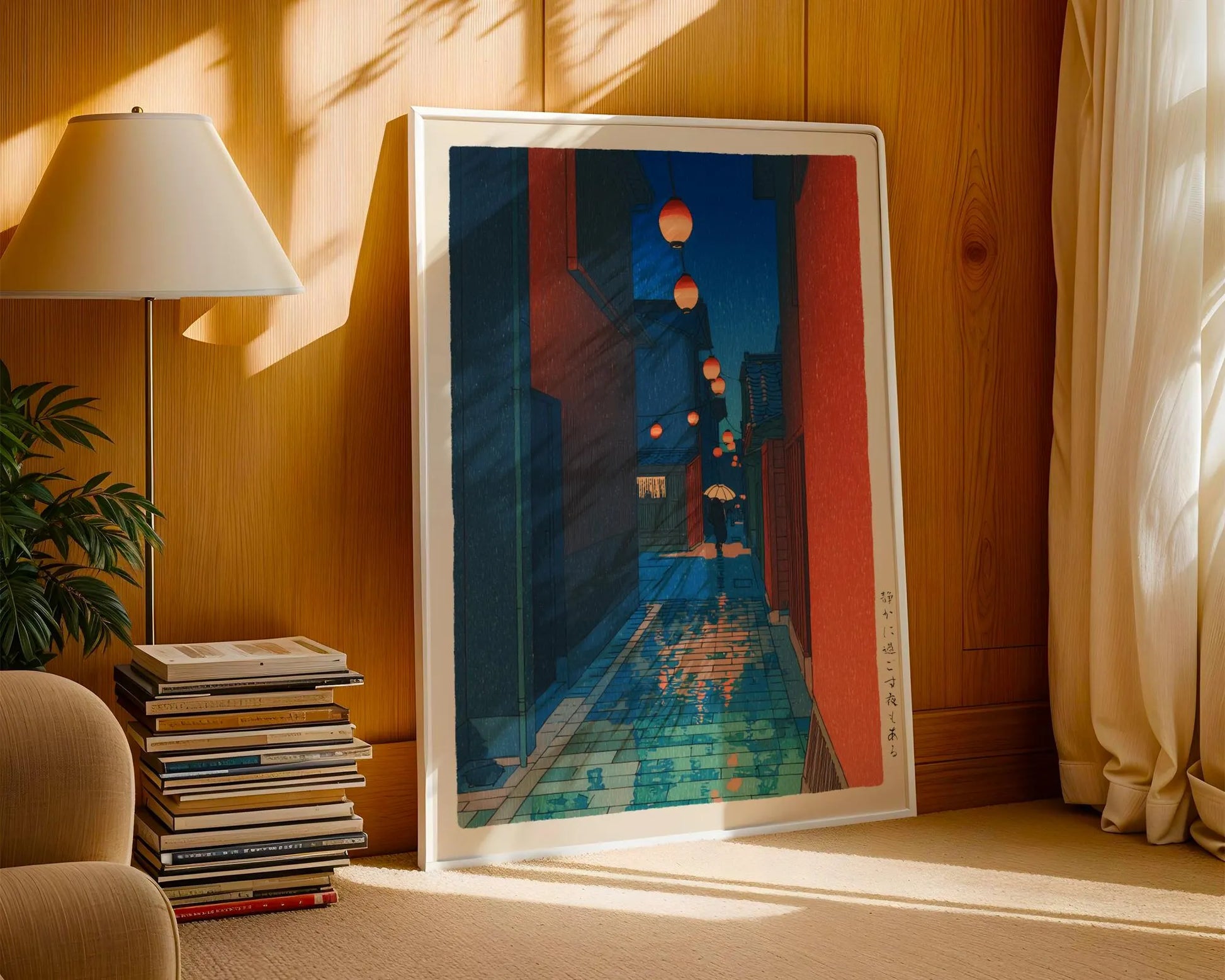 a large framed artwork depicting a city street at night, with colorful lights and buildings in the background. The artwork is placed on a wooden wall, and there is a lamp and a stack of books nearby.