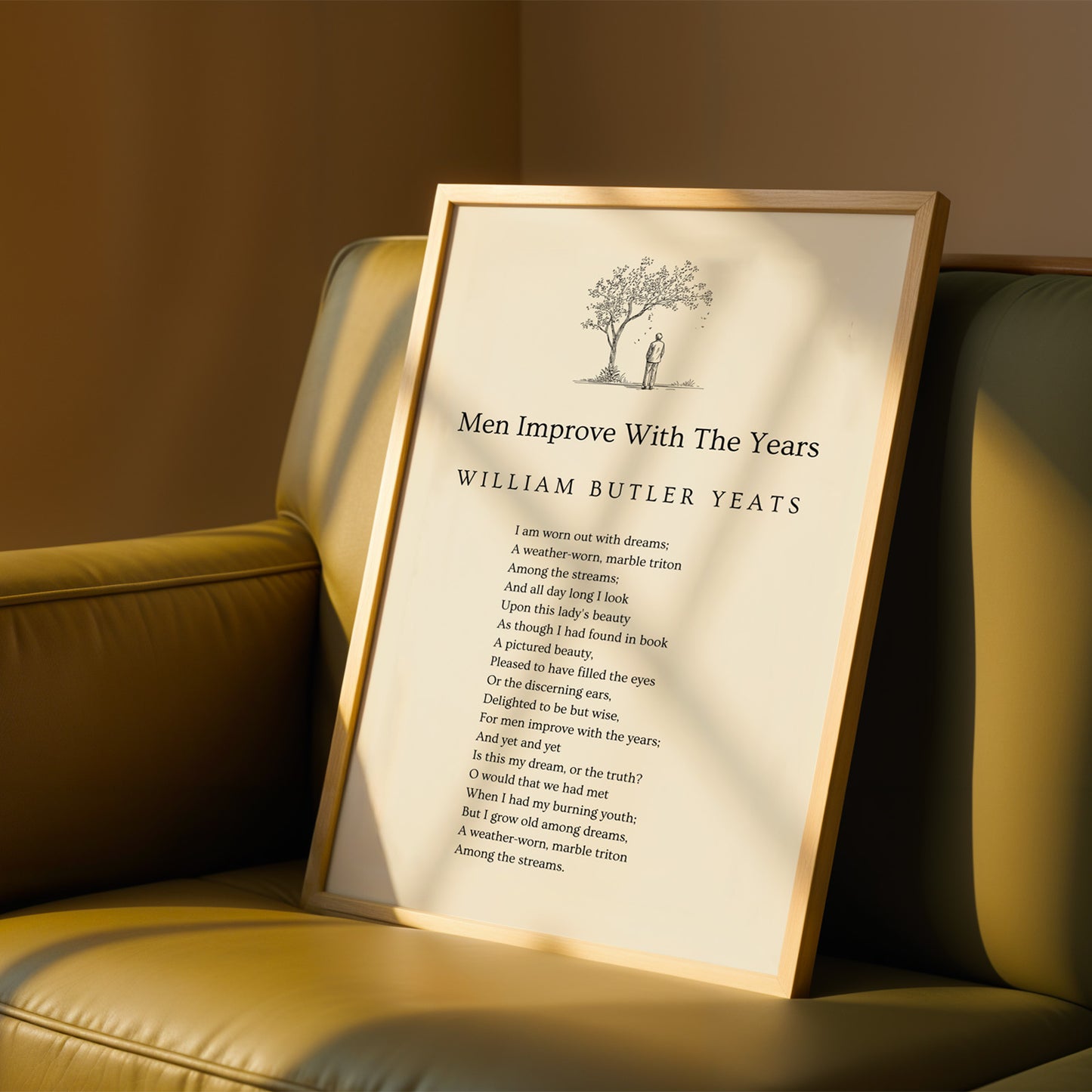 a framed poem titled "Men Improve With The Years" by William Butler Yeats, resting on a brown leather couch.