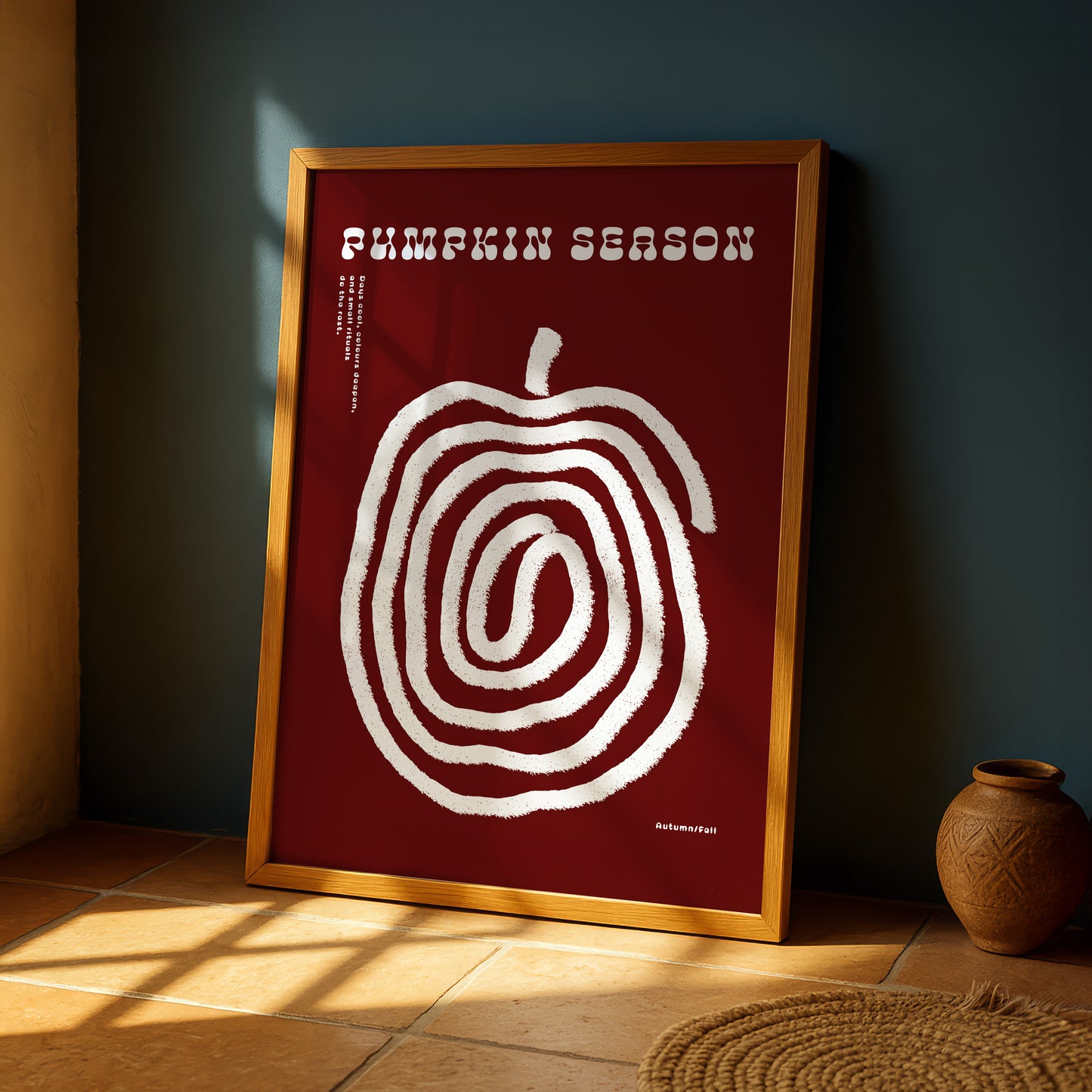 a framed poster with a large spiral design on a red background, placed on a wooden floor next to a small vase.