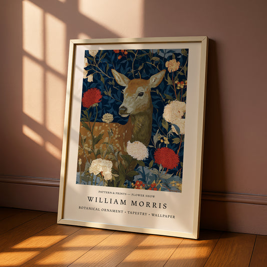 A framed poster of a deer surrounded by flowers and foliage, with the text "William Morris Pattern & Prints - Flower Show" and "Botanical ornament - Tapestry - Wallpaper" below the deer.