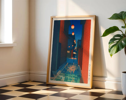 a framed artwork depicting a colorful street scene with lanterns hanging from the buildings.