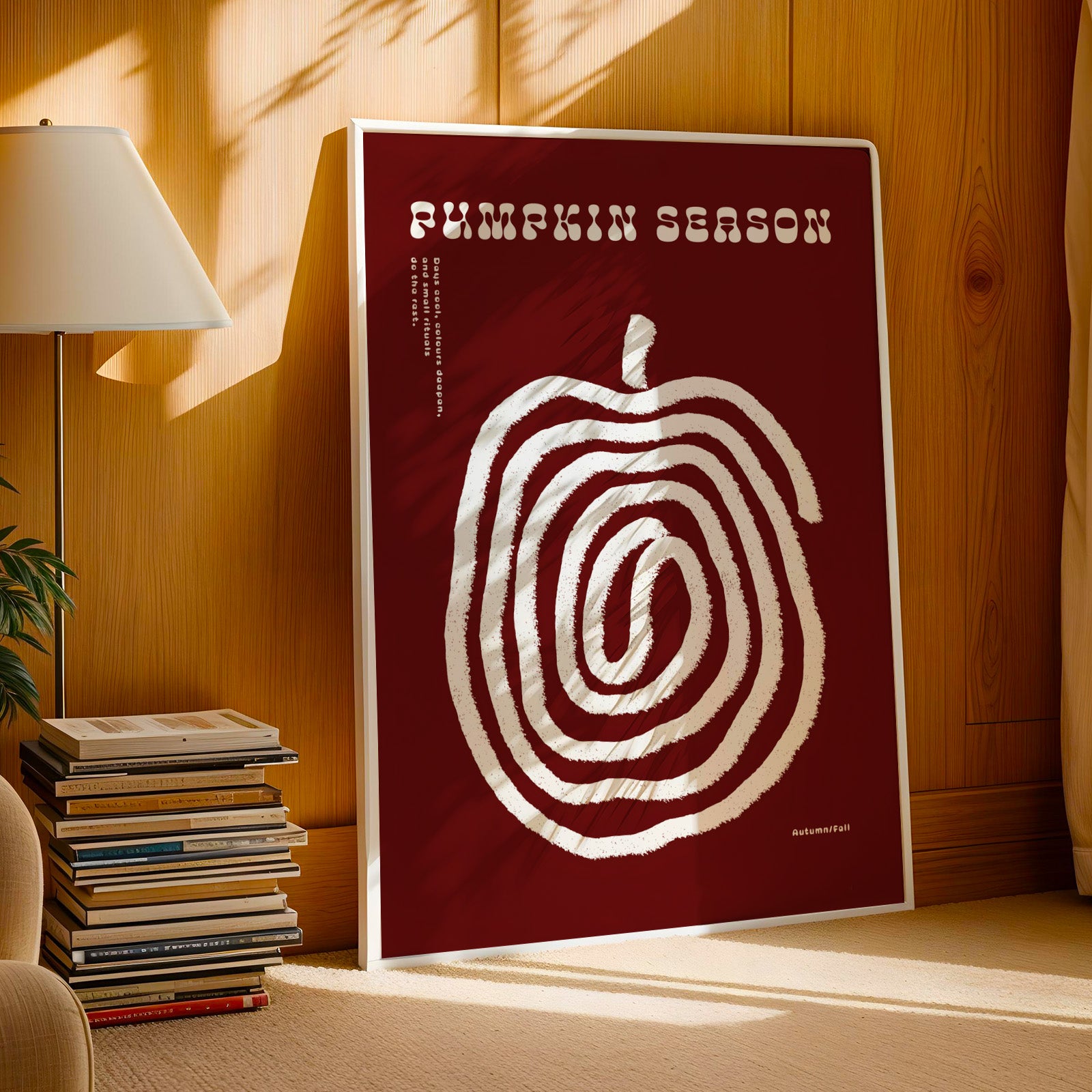 a poster with a large spiral design on a red background, placed on a wooden surface next to a stack of books and a lamp.