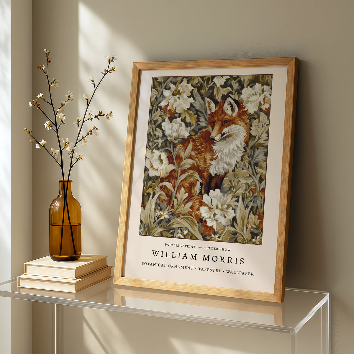 a framed painting of a fox surrounded by flowers, placed on a glass table next to a vase with white flowers.