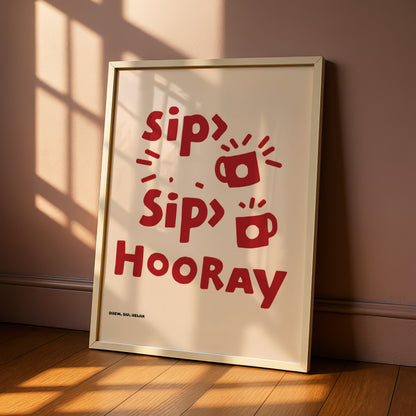 A framed poster with the text "Sip Sip Hooray" in red letters, along with some stylized illustrations of cups and saucers.