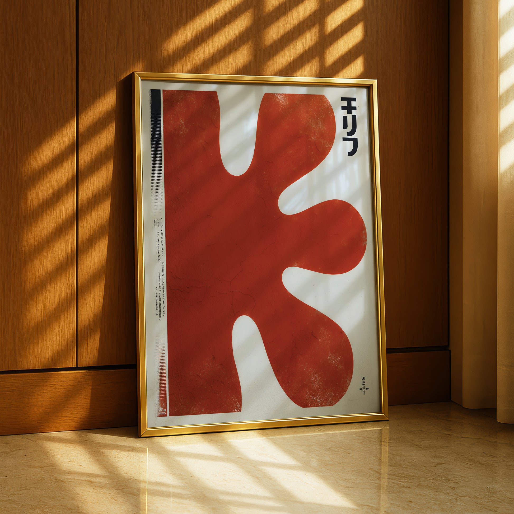 a large, abstract red shape with a black text element in a gold frame, placed on a wooden floor against a wooden wall.