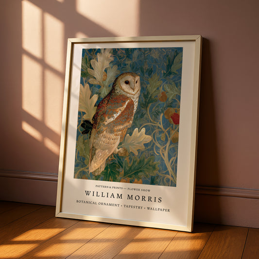 A framed print of a painting of a brown owl perched on a branch with leaves and flowers, displayed on a wooden floor against a pink wall.