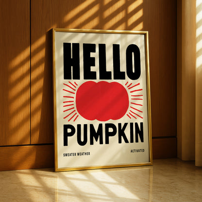A framed poster with the text "HELLO PUMPKIN" and a red pumpkin graphic, placed on a wooden floor near a window.