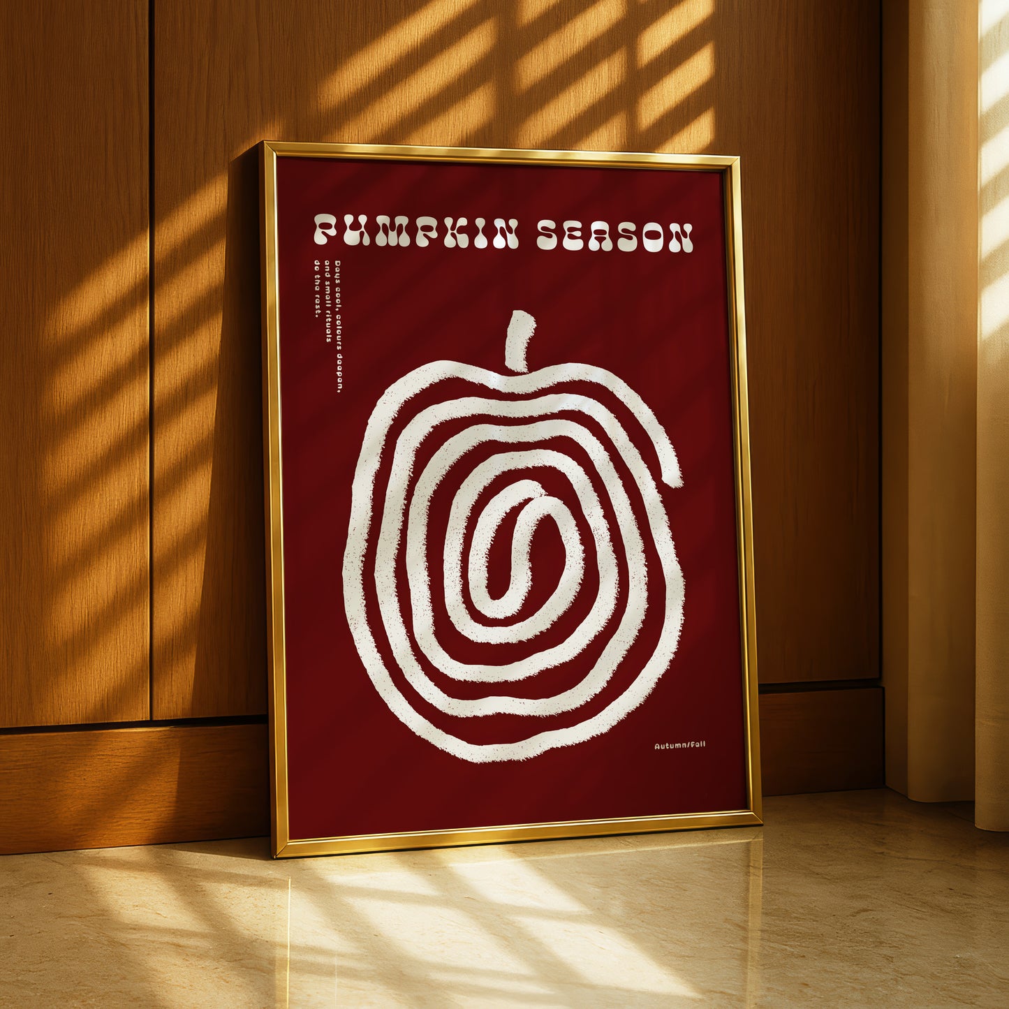 A framed poster with a red background and a white spiral design, placed on a wooden floor near a window.