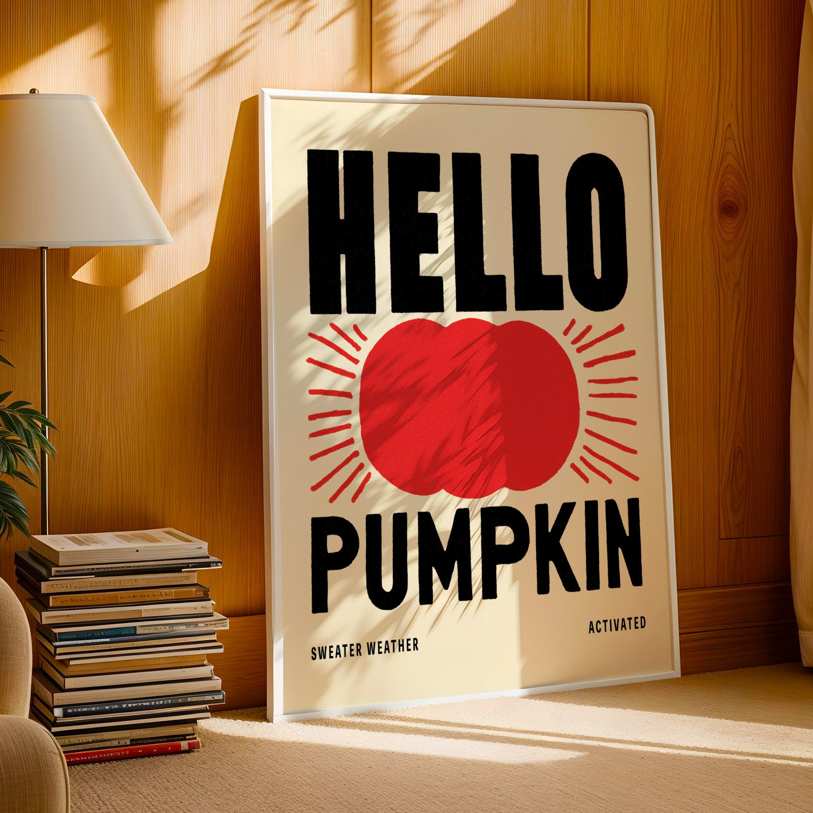 A poster with the text "HELLO PUMPKIN" and a red heart shape, placed on a wooden floor next to a stack of books and a lamp.