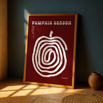 a framed poster with a large spiral design on a red background, placed on a wooden floor next to a small vase.