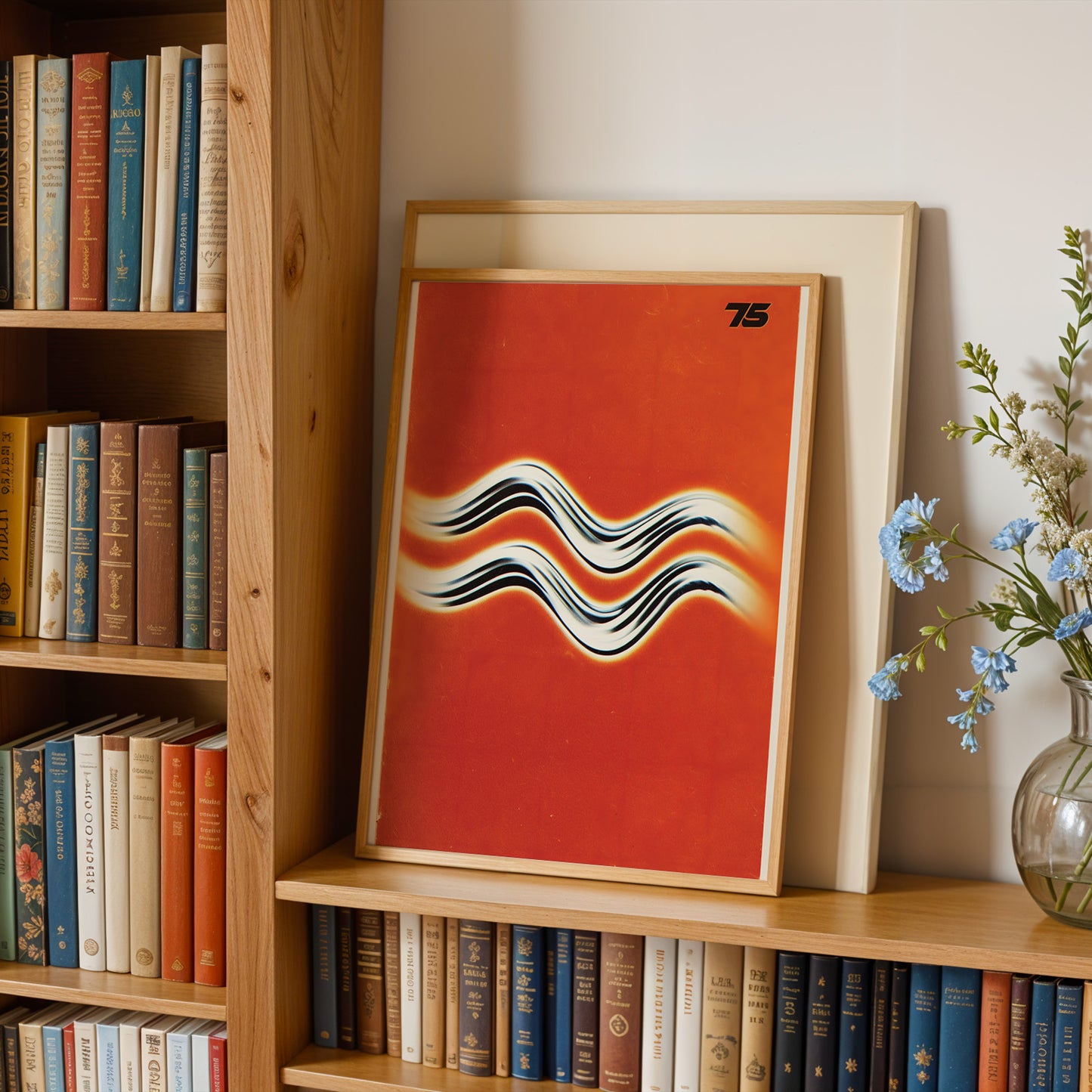a bookshelf with a framed poster of a wave-like design in red and white colors, along with a vase of blue flowers.