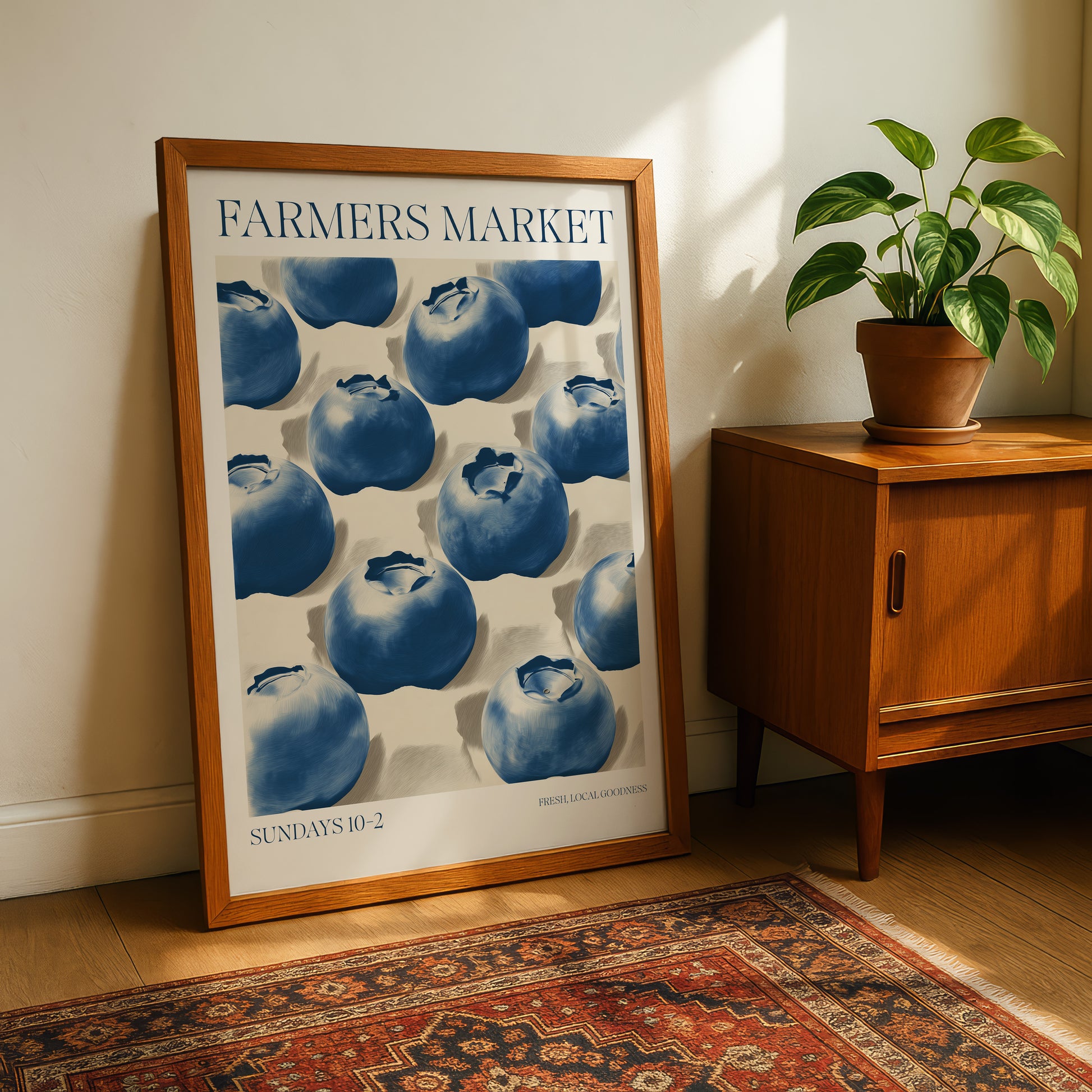 a framed poster of blueberries on a wall, with a wooden cabinet and a potted plant in the background.