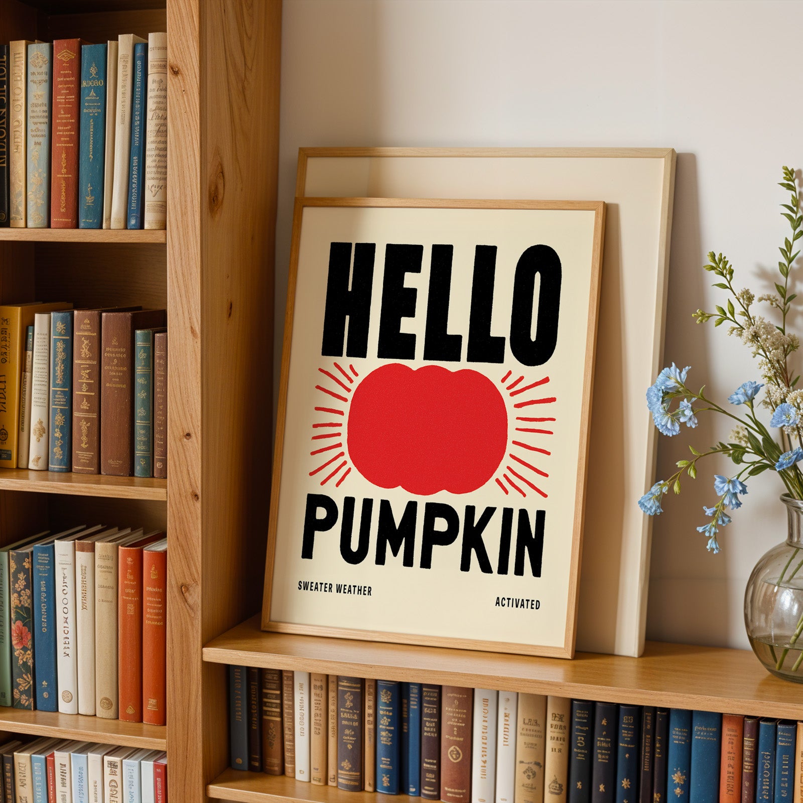a framed poster with the text "HELLO PUMPKIN" displayed prominently on a bookshelf.