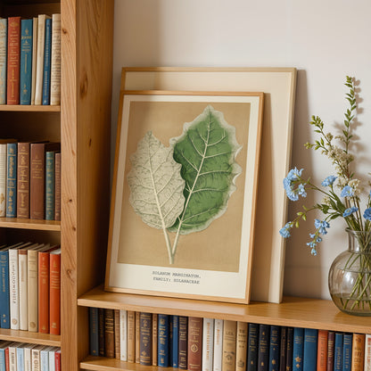 a wooden bookshelf with a framed botanical illustration of two leaves, a vase of blue flowers, and a collection of books.