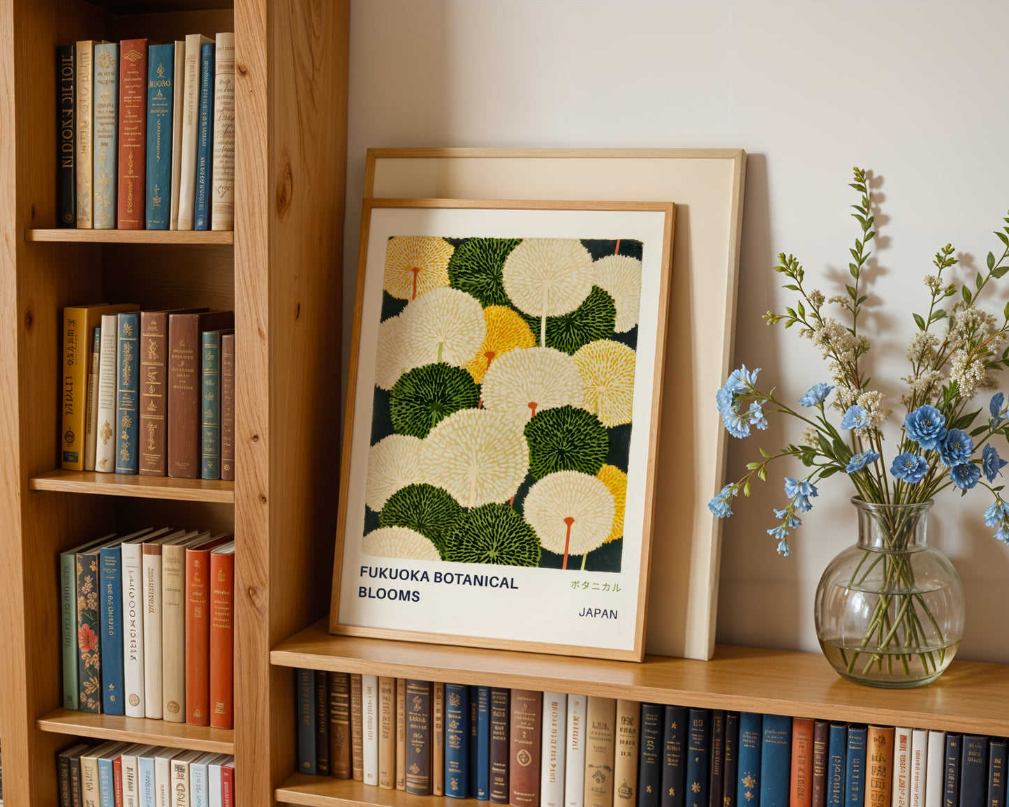 a wooden bookshelf with a framed print of a floral design on the top shelf, a vase of blue flowers on the bottom shelf, and a collection of books on the shelves below.