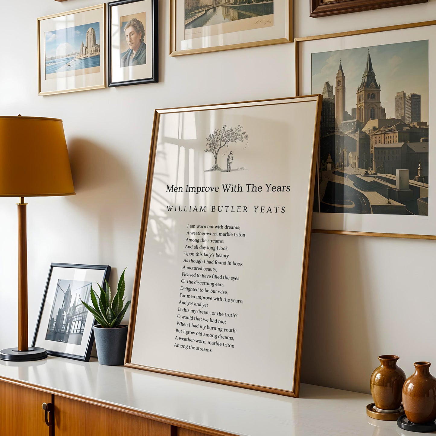 a framed poem titled "Men Improve With The Years" by William Butler Yeats, displayed on a shelf with various framed pictures and a lamp.