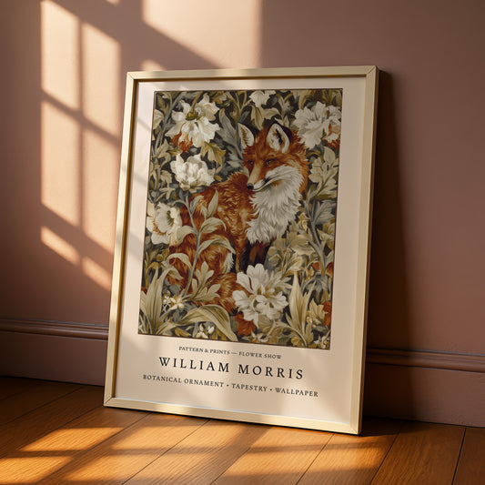 A framed print of a fox surrounded by a floral pattern, placed on a wooden floor against a pink wall.