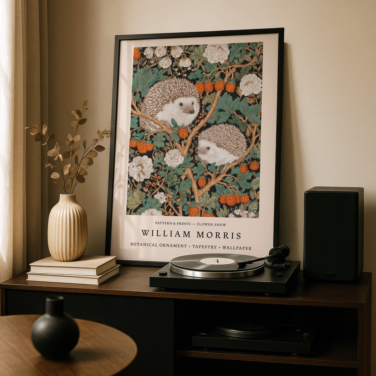 a framed painting of two hedgehogs on a branch with flowers, placed on a wooden shelf above a record player and a vase.