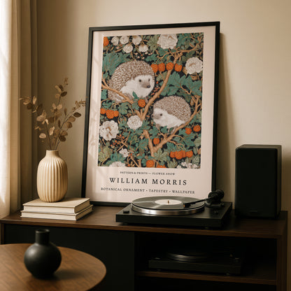 a framed painting of two hedgehogs on a branch with flowers, placed on a wooden shelf above a record player and a vase.